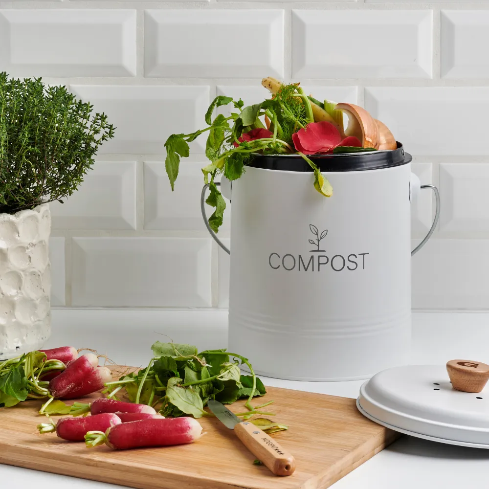 Seau à compost avec filtre dans une cuisine avec une planche à découper avec des radis rose dessus